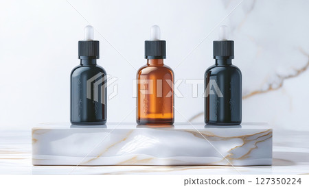 Three glass dropper bottles, arranged on a sleek marble base. Three glass dropper bottles, arranged on a sleek marble base. 127350224