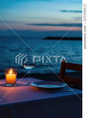 Candlelit Seaside Dinner Table for One at Twilight with Ocean Horizon 127350317