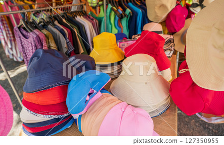 Colorful traditional hats display at rural Thai street market where local vendors sell handmade headwear to tourists during sunny day creating vibrant shopping experience in countryside Thailand Colorful traditional hats display at rural Thai street market where local vendors sell handmade headwear to tourists during sunny day creating vibrant shopping experience in countryside Thailand 127350955