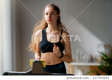 Young woman running on a treadmill indoors 127353041
