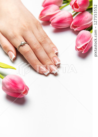 Woman showing french manicure and pink tulips on white background Woman showing french manicure and pink tulips on white background 127353552