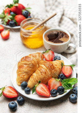 Delicious breakfast with croissants, coffee, berries and honey enjoying morning meal 127353555