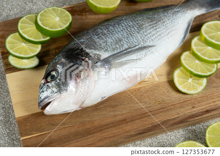 Raw Uncooked Dorado Fish with Fresh Sliced Lime Ready to Cook. Raw Uncooked Dorado Fish with Fresh Sliced Lime Ready to Cook. 127353677