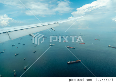 Airplane arriving over sea with cargo ships in Singapore 127353721