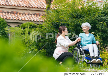 Senior woman in wheelchair and care staff in garden Senior woman in wheelchair and care staff in garden 127353998