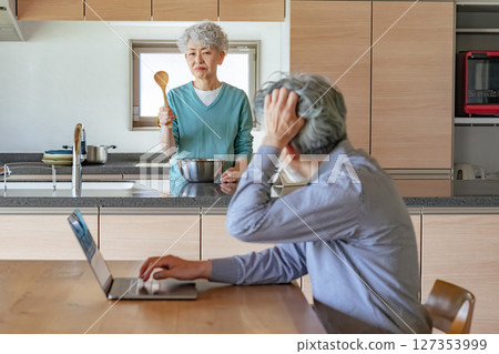 Senior woman getting angry at her husband who works from home Senior woman getting angry at her husband who works from home 127353999