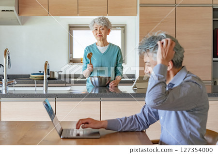 Senior woman getting angry at her husband who works from home Senior woman getting angry at her husband who works from home 127354000