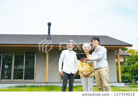 一名男工作人員在房子前向一對老年夫婦講解一些事情 一名男工作人員在房子前向一對老年夫婦講解一些事情 127354018