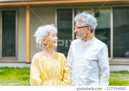 Smiling senior couple standing in front of their house 127354062