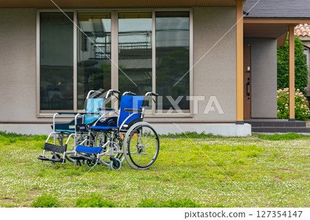 Two wheelchairs in front of a house 127354147
