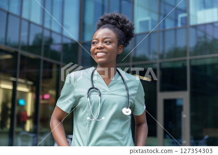 Confident african american female doctor standing in the clinics yard 127354303