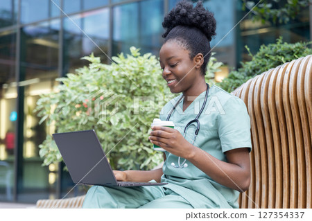 African american young doctor sitting on the bench and having coffee 127354337