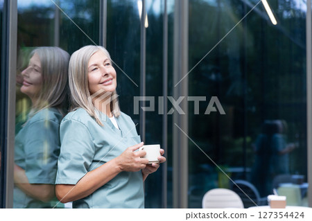 Mature caucasian female doctor having coffee and looking relaxed 127354424