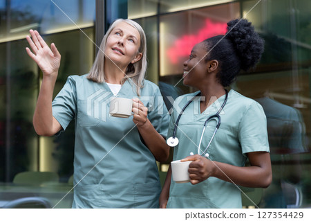Two female doctors with cups with coffee in the elevator talking 127354429