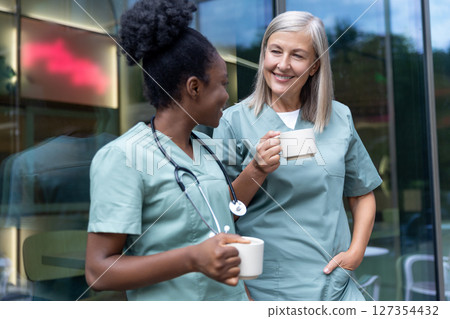 Two female doctors with cups with coffee in the elevator talking 127354432