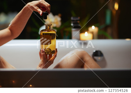 Hands Opening Essential Oil Bottle in Bath 127354526