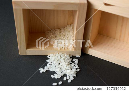 A little bit of rice spilled from a wooden measuring cup A little bit of rice spilled from a wooden measuring cup 127354912