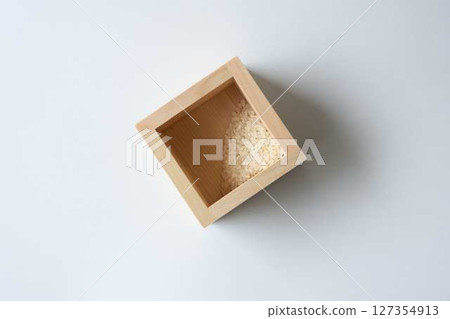 A small amount of rice left in a wooden box on a white background A small amount of rice left in a wooden box on a white background 127354913