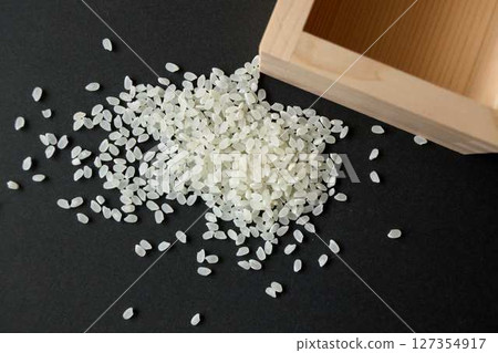 Empty measuring cup and spilled rice on a black background Empty measuring cup and spilled rice on a black background 127354917