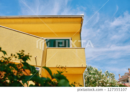 Residential building facade with windows and terrace against blue sky Residential building facade with windows and terrace against blue sky 127355107