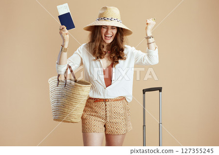 smiling elegant woman in blouse and shorts rejoicing on beige 127355245
