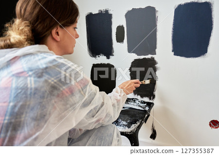 Woman Testing Black Paint Samples on Wall During Apartment Renovation Woman Testing Black Paint Samples on Wall During Apartment Renovation 127355387
