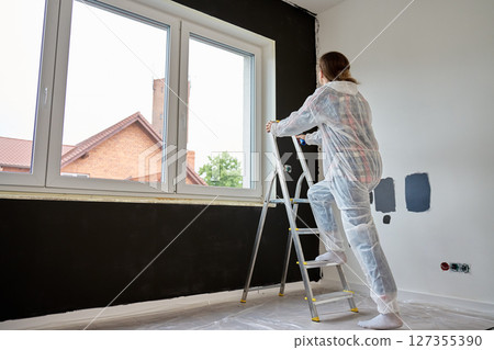 Woman preparing to paint interior wall during apartment renovation 127355390