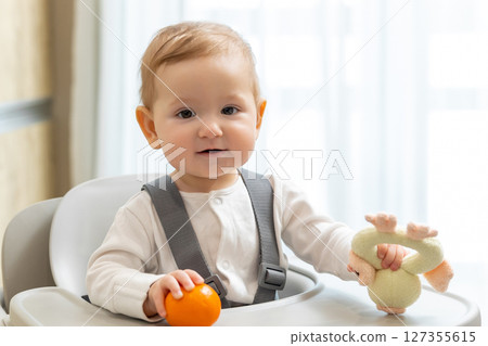 Cute small baby boy sitting in his chair and playing Cute small baby boy sitting in his chair and playing 127355615
