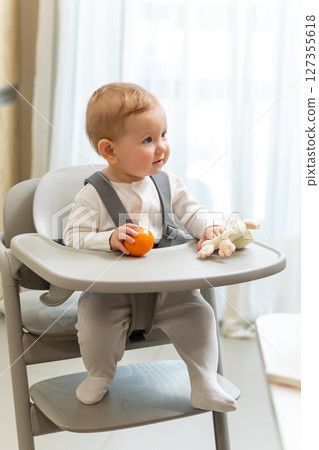 Cute small baby boy sitting in his chair and playing Cute small baby boy sitting in his chair and playing 127355618