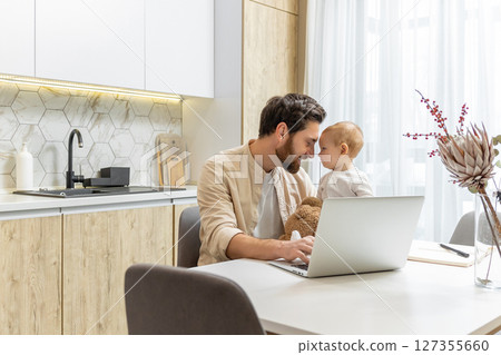 Bearded young caucasian man working from home while taking care of his little son Bearded young caucasian man working from home while taking care of his little son 127355660