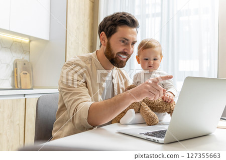 Young bearded man having a video call and holding his little son 127355663