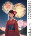 A woman wearing a yukata participating in a fireworks display 127355859