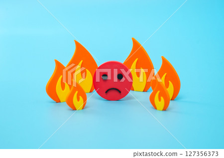Sad face surrounded by fire. Severe stress, mental problems and illnesses. Severe heat and uncomfortable temperature. Emotional burnout 127356373
