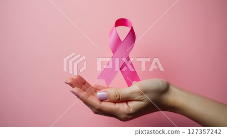 Support for breast cancer awareness represented by a pink ribbon held in an open hand against a soft pink background Support for breast cancer awareness represented by a pink ribbon held in an open hand against a soft pink background 127357242