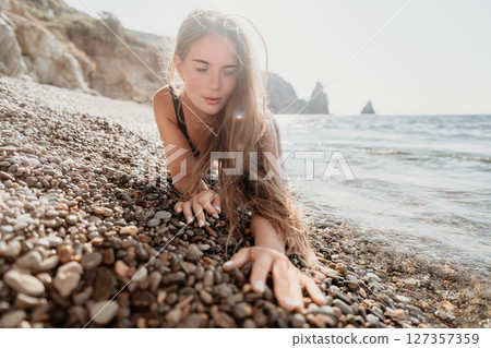 Woman Reaching for the Ocean on a Pebble Beach 127357359