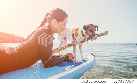 Woman Dog Paddleboard - A woman and her dog enjoy paddleboarding on a sunny day. Woman Dog Paddleboard - A woman and her dog enjoy paddleboarding on a sunny day. 127357397