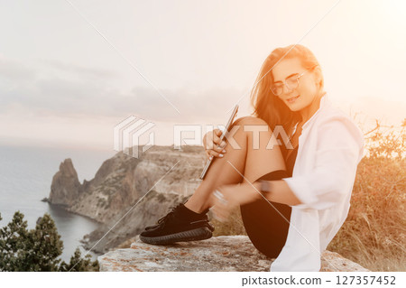 Woman, Sunset, Cliff: Happy woman enjoying a beautiful sunset view from a cliff overlooking the ocean. 127357452