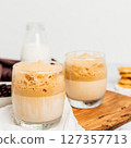 Iced or frappe coffee smoothie on a glass cup and Roasted coffee beans, and milk on marble backdrop.  127357713