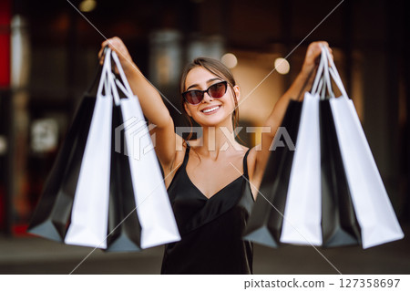 Shopping bags in the hands. Fashion woman with packages after shopping. Black friday, sale. 127358697