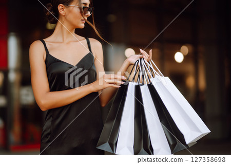 Shopping bags in the hands. Fashion woman with packages after shopping. Black friday, sale. Shopping bags in the hands. Fashion woman with packages after shopping. Black friday, sale. 127358698
