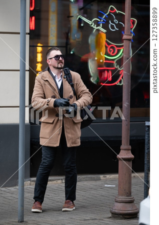 Captured in urban exploration, a stylish photographer admires neon cat art while searching for the perfect shot during a chilly afternoon in the bustling city Captured in urban exploration, a stylish photographer admires neon cat art while searching for the perfect shot during a chilly afternoon in the bustling city 127358899