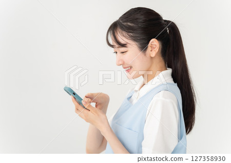 穿著圍裙、拿著智慧型手機的年輕女子 127358930