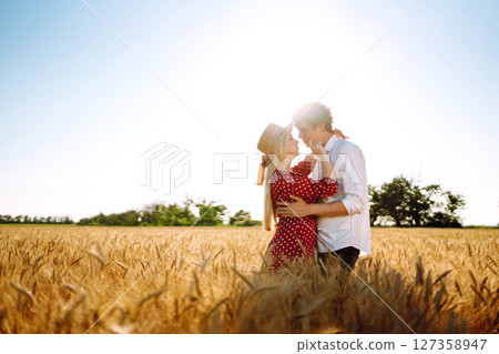 Young happy couple hugging on a wheat field, on the sunset. Enjoying time together. 127358947
