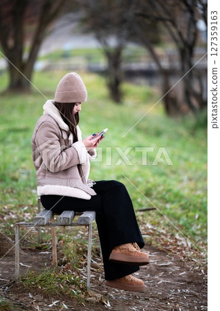 Surrounded by the serene beauty of a tranquil park, I find myself embracing nature, yet paradoxically lost in the digital world of my smartphone. 127359163