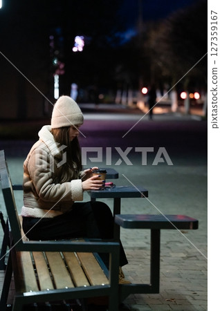 Sipping warmth while the night embraces a quiet urban park under the soft glow of streetlights and the crisp winter air 127359167