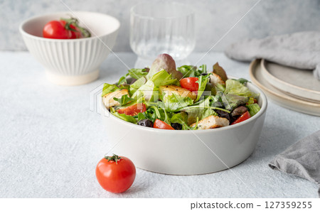 Vegetarian salad with lettuce, tomatoes, croutons and olives in a bowl on a light background 127359255