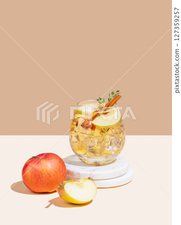 Apple cocktail or cider in a glass with ice, cinnamon and thyme, on a marble stand Apple cocktail or cider in a glass with ice, cinnamon and thyme, on a marble stand 127359257