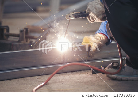 Construction Worker hands using Welding machinery iron metal sparking. Men hands wear protective glove Hot flame metal work cutting fire iron workshop. Locksmith use Welding machine cut metal process Construction Worker hands using Welding machinery iron metal sparking. Men hands wear protective glove Hot flame metal work cutting fire iron workshop. Locksmith use Welding machine cut metal process 127359339