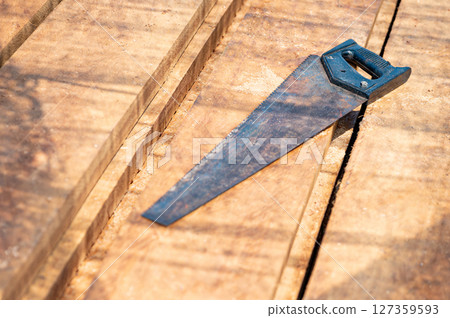 Rustic old hand saw on timber stack at construction site Rustic old hand saw on timber stack at construction site 127359593