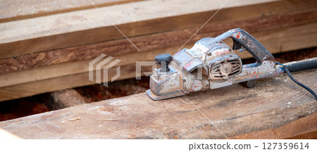 Rustic old electric planer on timber stack or wooden plank with sawdust spreading around 127359614
